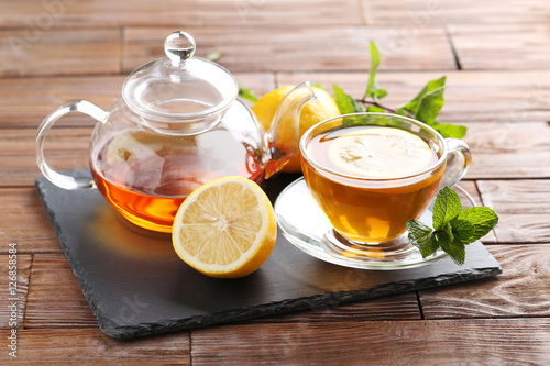 Cup of tea with mint and lemon on brown wooden table