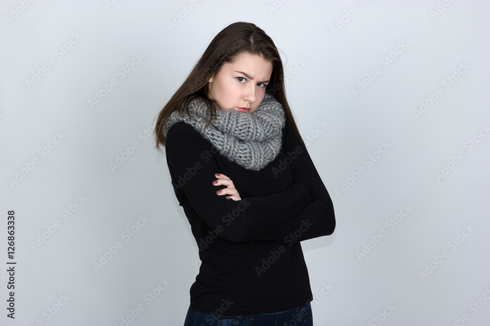 Portrait of a pretty offended sad  gir in turtleneck sweater   with scarf   over gray background  looking at camera