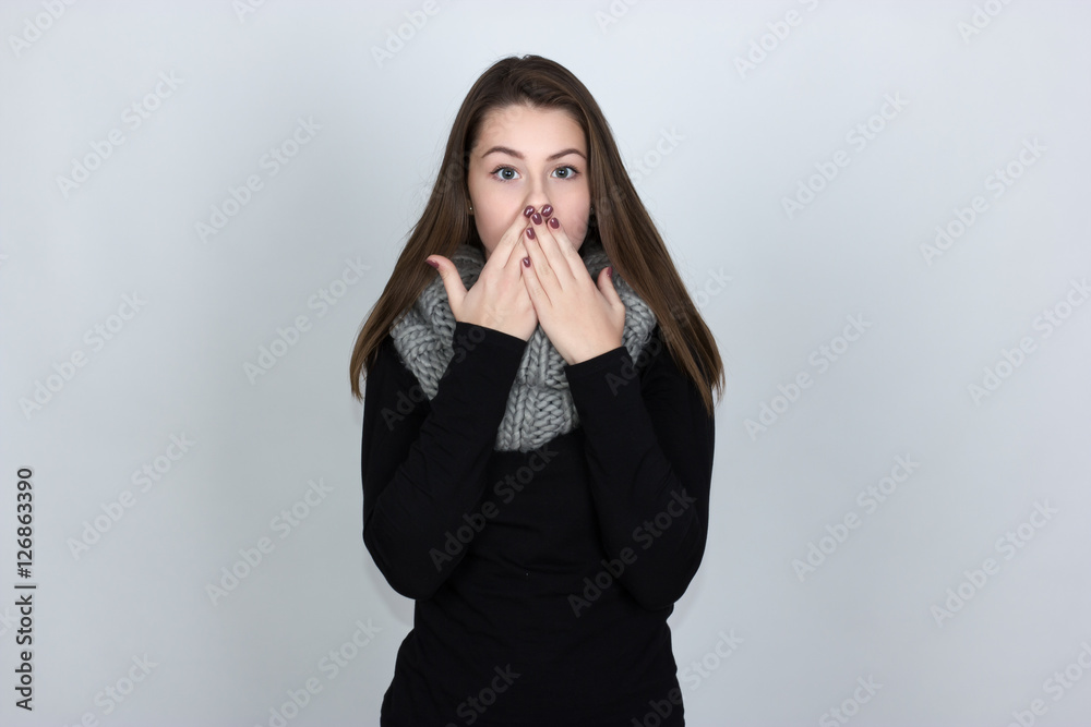Portrait of a pretty woman in turtleneck sweater covering her mouthover gray background and displays a stop sign with her hand Portrait of a pretty woman in turtleneck sweater covering her mouthover gray background and displays a stop sign with her hand