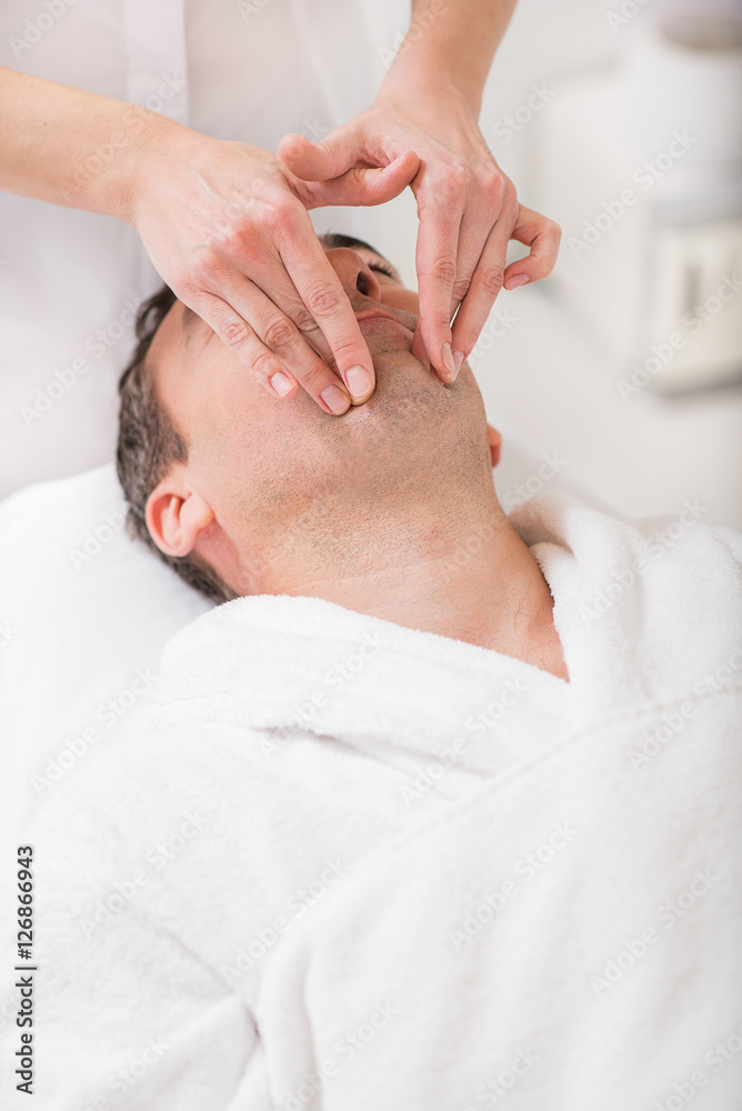 Masseuse massaging male face at spa Masseuse massaging male face at spa