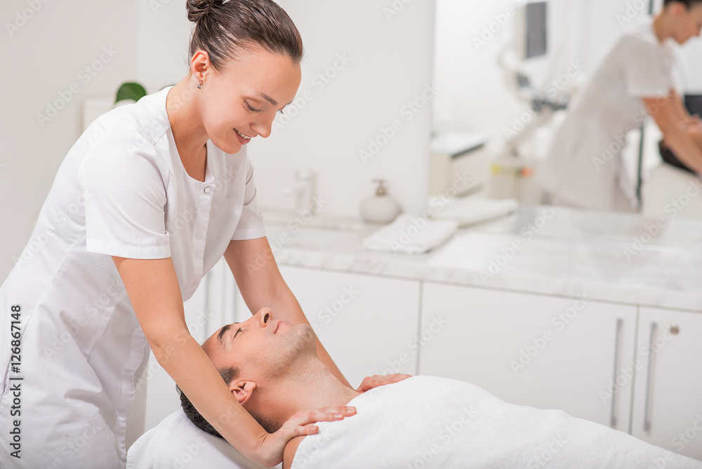 Obraz premium Joyful masseuse massaging male shoulders