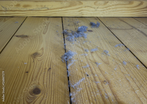 Dust dirt and crumbles on the wood floor under the bed. Home dust on the wooden floor. photo