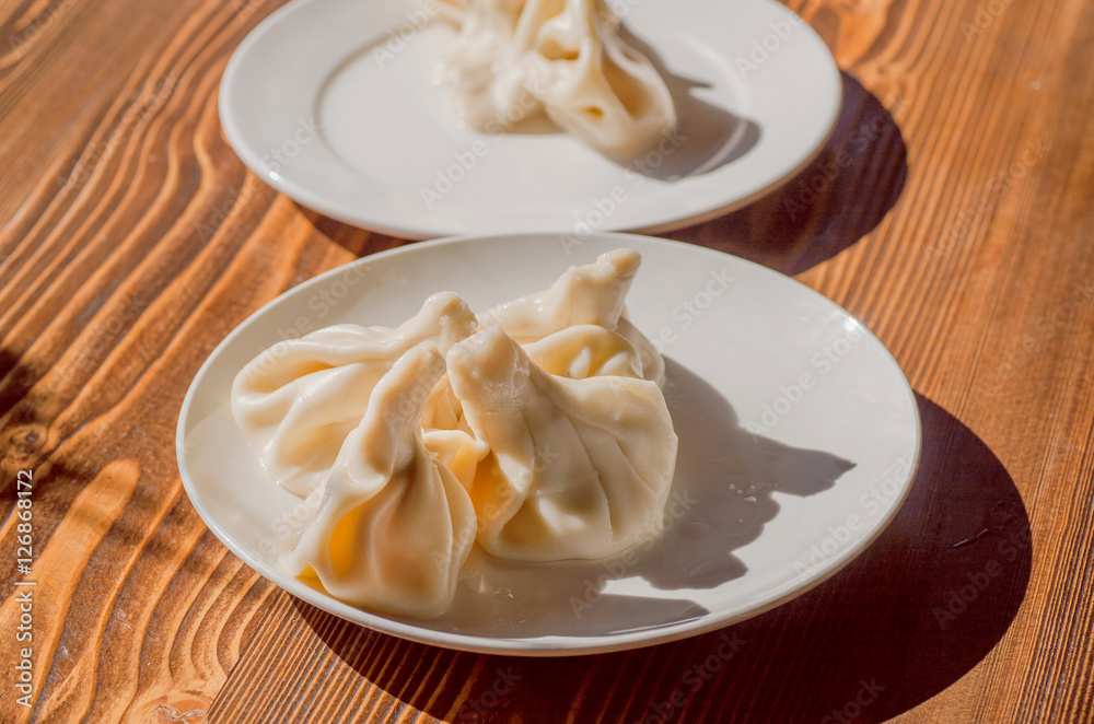 Kitchen with Khinkali dish on plate. Georgian dumpling with meat, or cheese, or mushrooms. Traditional Caucasian cuisine Kitchen with Khinkali dish on plate. Georgian dumpling with meat, or cheese, or mushrooms. Traditional Caucasian cuisine