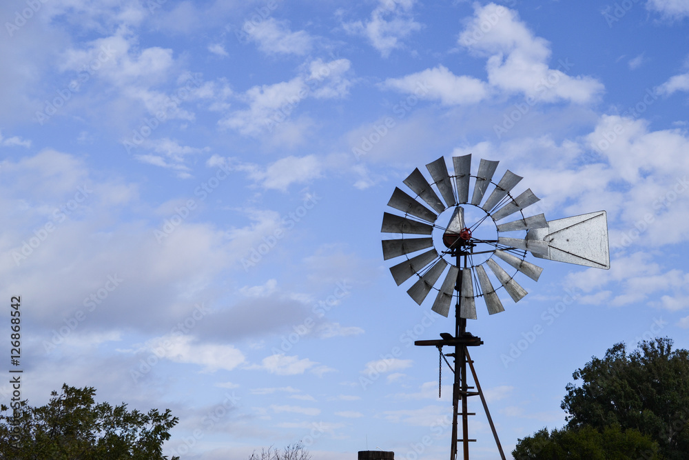 Closeup on upper portion of Vintage Wind Mill in Central California against partly cloudy sky