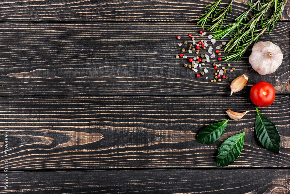 fresh rosemary, salt, pepper and garlic on a black wooden backgr fresh rosemary, salt, pepper and garlic on a black wooden backgr