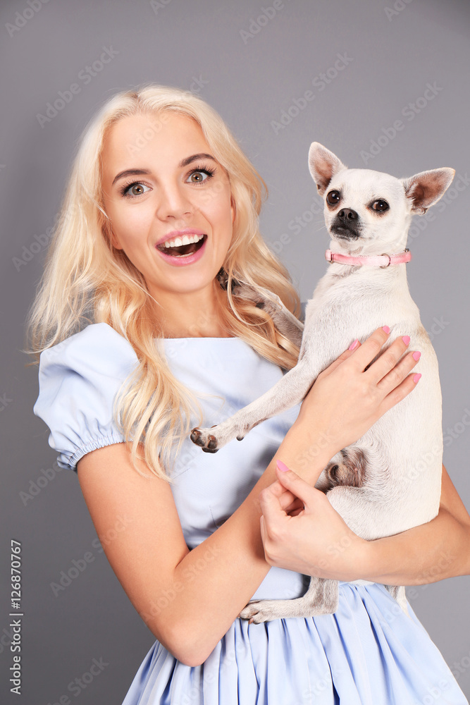 Beautiful girl holding cute dog on grey background Beautiful girl holding cute dog on grey background