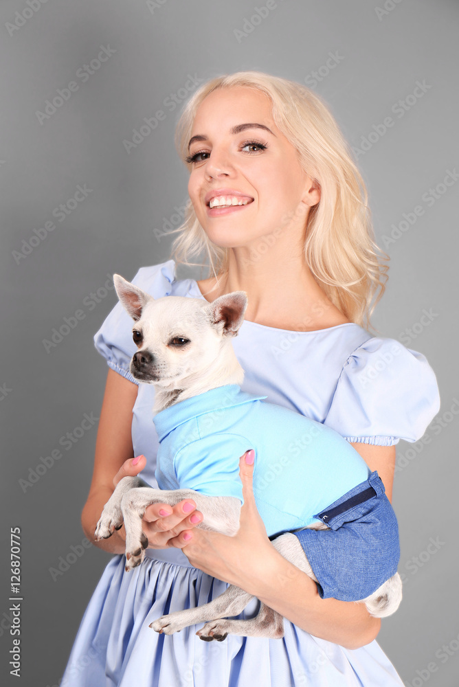 Beautiful girl holding cute dog on grey background Beautiful girl holding cute dog on grey background