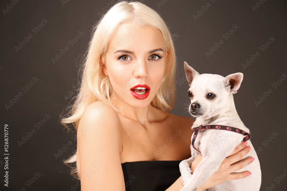 Beautiful girl holding cute dog on dark background Beautiful girl holding cute dog on dark background