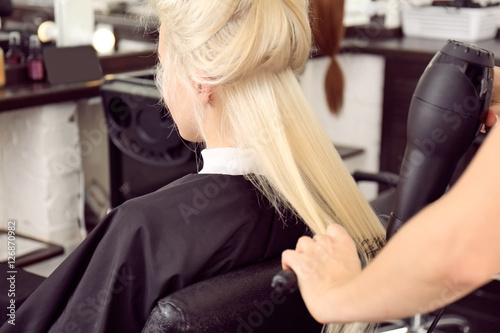 Hairdresser drying blonde's hair at salon