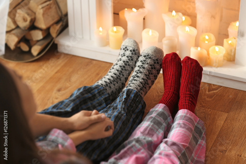 Couple legs resting in front of fireplace at home in Christmas holiday