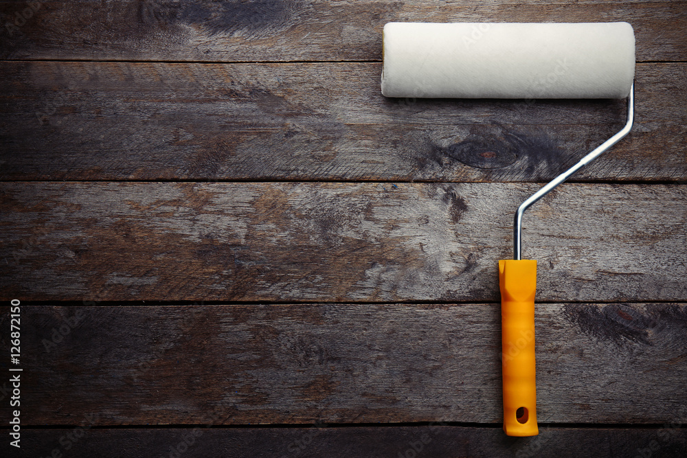 Obraz premium Painting roller on wooden background, top view