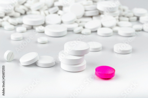 Bunch of white tablets. Scattered pills. Single pink pill