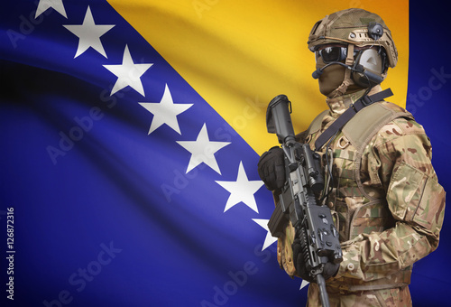 Soldier in helmet holding machine gun with flag on background series - Bosnia and Herzegovina