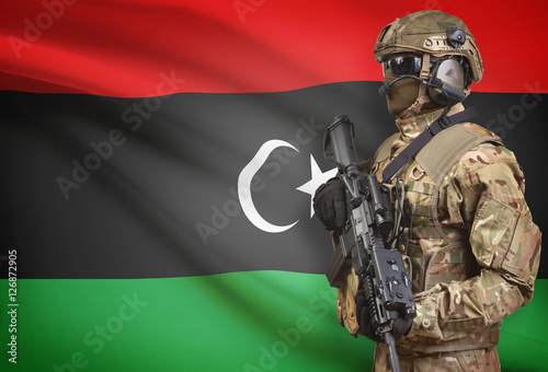 Soldier in helmet holding machine gun with flag on background series - Libya