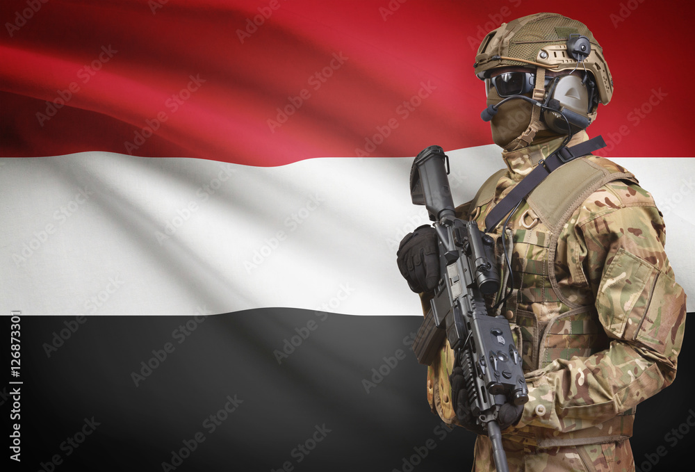 Soldier in helmet holding machine gun with flag on background series - Yemen Soldier in helmet holding machine gun with flag on background series - Yemen