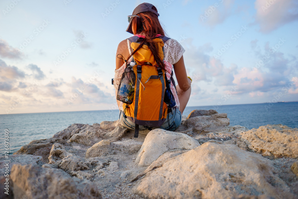 Female tourist sitting on rock and looking at sea Female tourist sitting on rock and looking at sea