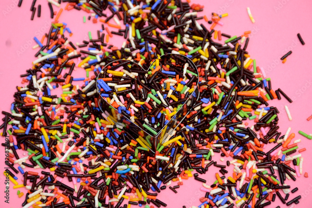 Colorful chocolate sprinkles on pink background