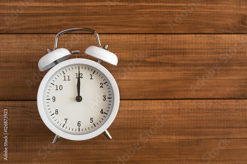 White retro clock on wooden background.