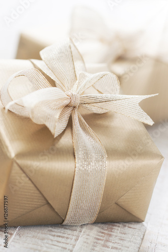 Golden gift boxes with beautiful ribbon and bow on a bright shin