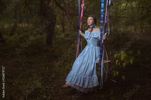 Woman in the woods on a swing.