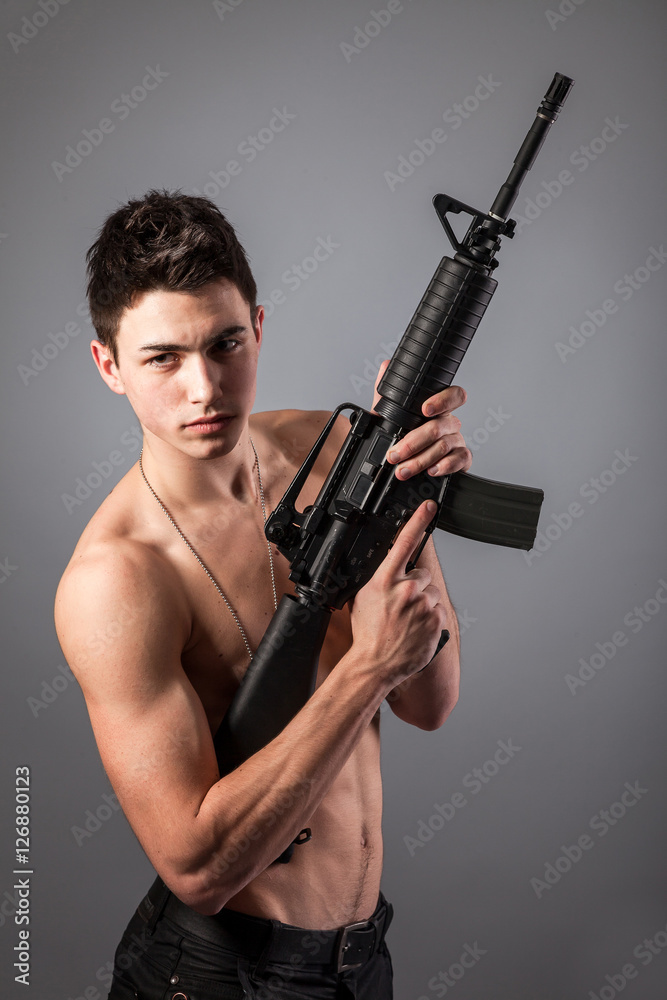 Handsome bare-chested soldier is holding a rifle Handsome bare-chested soldier is holding a rifle