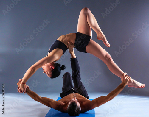 Young couple practicing acro yoga on mat in studio together photo