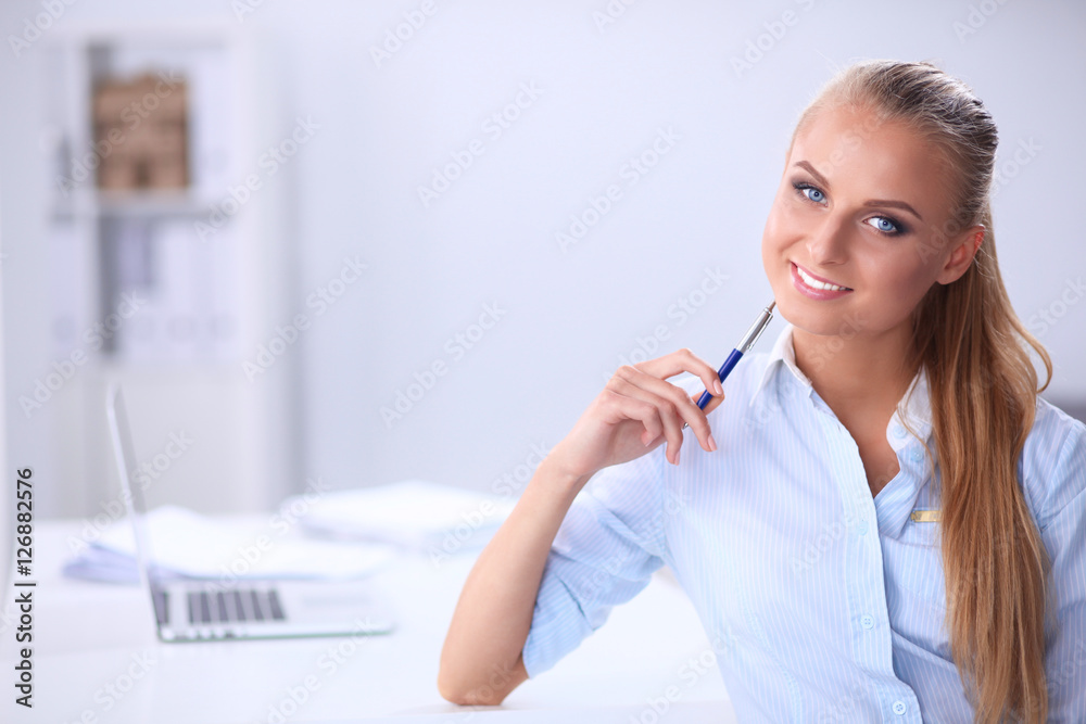 Attractive businesswoman sitting on a desk with laptop in the office Attractive businesswoman sitting on a desk with laptop in the office