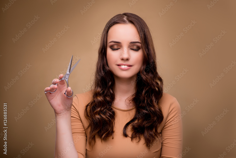 Obraz premium Beautiful woman with scissors cutting her hair