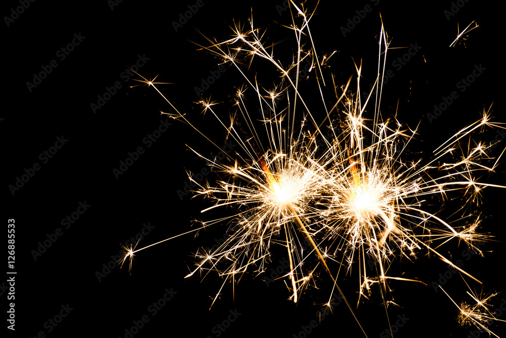 Two burning sparklers at black background