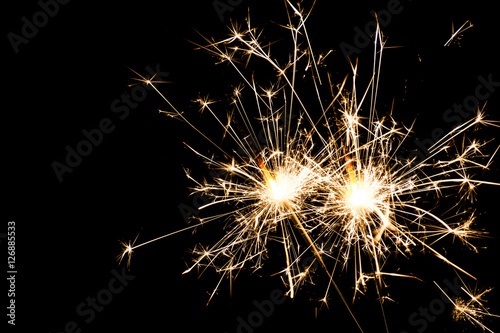 Two burning sparklers at black background