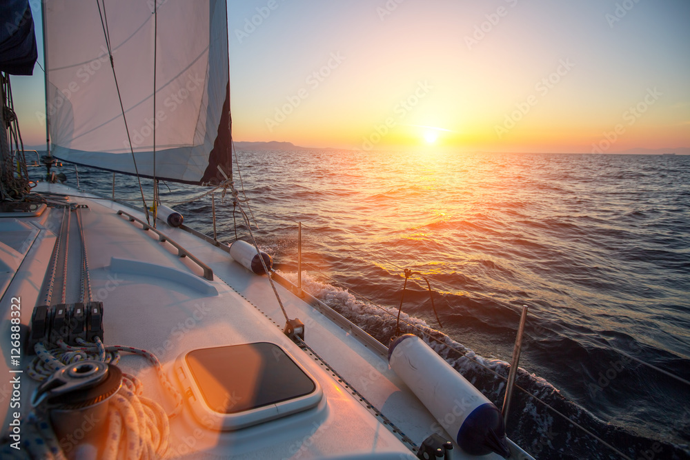Fototapeta premium Amazing sunset at sea shot of a luxery yacht boat. Sailing in the wind through the waves.