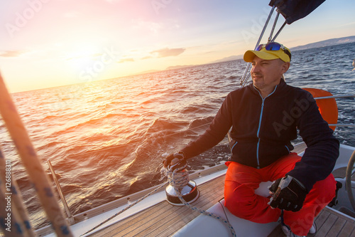 Man sits on yacht during sunset. Luxury sailing boats. Travel, vacation.