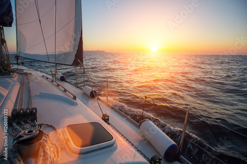 Amazing sunset at sea shot of a luxery yacht boat. Sailing in the wind through the waves.