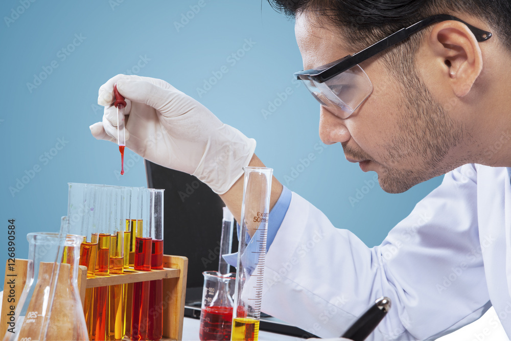 Young chemist looking at chemical liquid Young chemist looking at chemical liquid