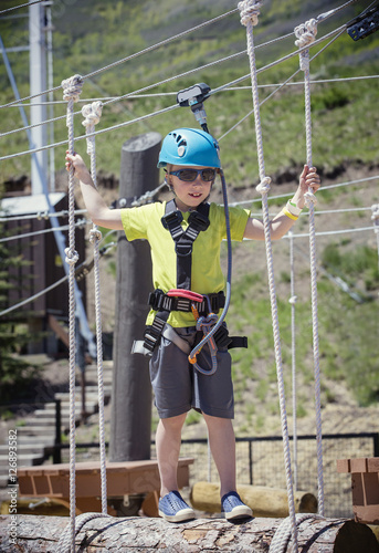 Little boy climbing on an outdoor ropes course