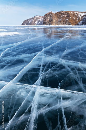 Lake Baikal in winter. Beautiful pattern of cracks on the transparent ice. Focus on the ice surface