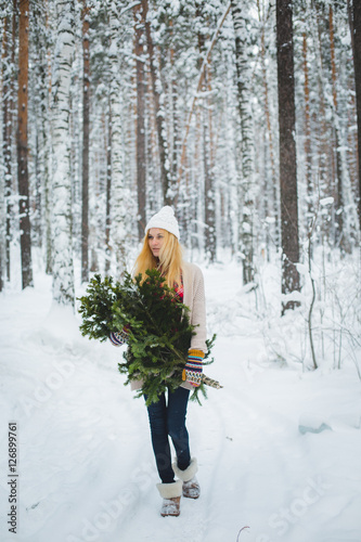 girl in winter forest holds branches in his hands