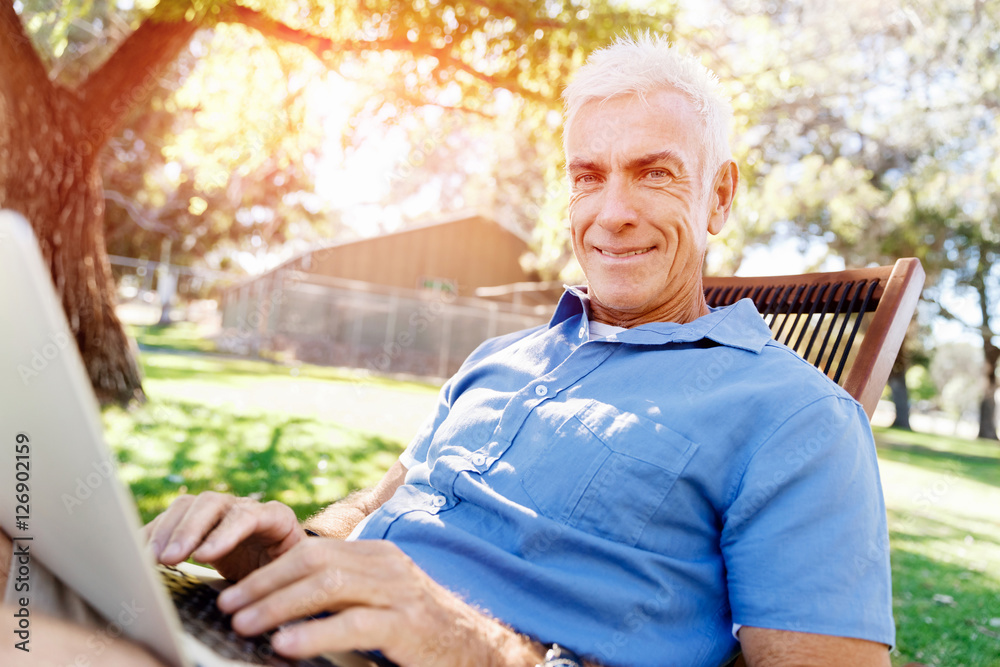 Senior man with notebook sitting in the park Senior man with notebook sitting in the park