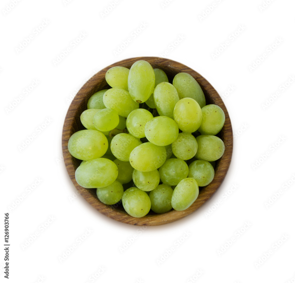 Grapes in a wooden bowl isolated on white background. Green grapes Kish Mish. Top view. Grapes in a wooden bowl isolated on white background. Green grapes Kish Mish. Top view.