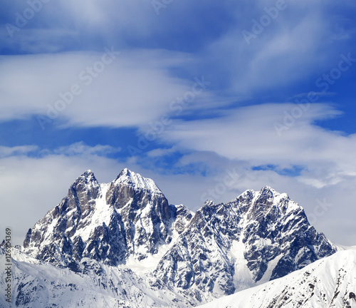 Mounts Ushba and Chatyn and blue sky with clouds in winter wind