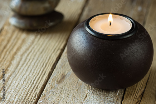 White tea light in a black wood candle holder and zen balanced stones in background copyspace for text  harmony concept