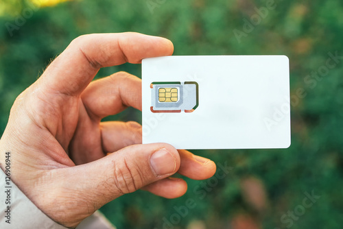 Male hand holding mobile phone SIM card photo