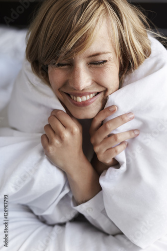 Blond woman snuggled up in duvet