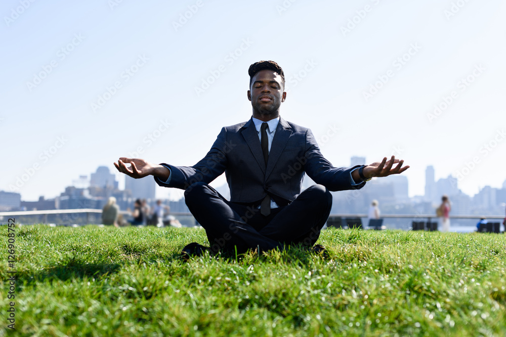 Young african businessman meditating outside at the lawn Young african businessman meditating outside at the lawn