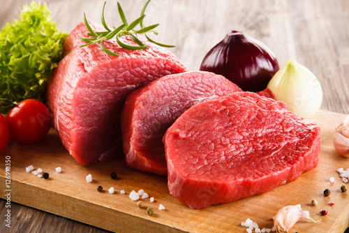 Fresh raw beef on cutting board and vegetables