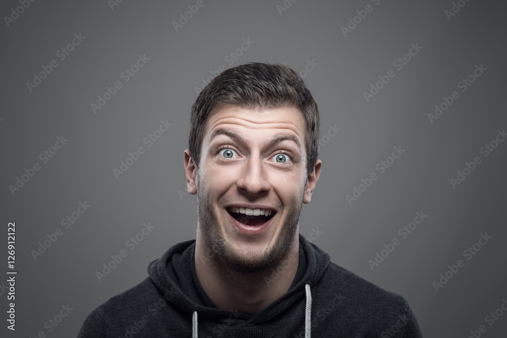 Moody portrait of surprised expressive young man looking at camera over gray background Moody portrait of surprised expressive young man looking at camera over gray background