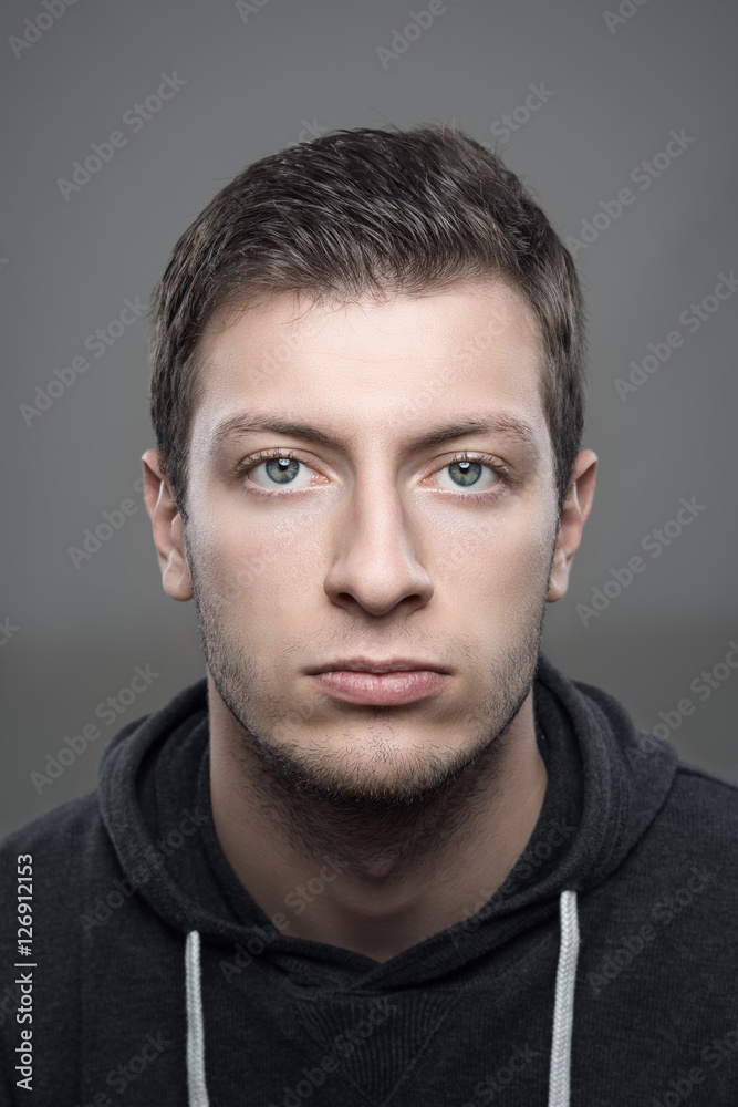 Fototapeta premium Close up moody vertical portrait of young casual man wearing sports hoodie looking at camera
