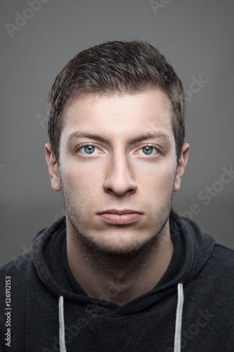 Close up moody vertical portrait of young casual man wearing sports hoodie looking at camera