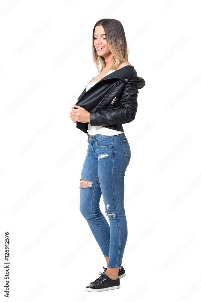 Pretty smiling shy casual girl wearing leather jacket, ripped jeans and  black sneakers looking down. Full body length portrait isolated over white  background Stock Photo | Adobe Stock