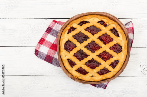 Pie with cherry jam on wooden background.